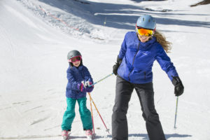 mom pulling daughter on skis